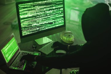 Hacker karanlık odada bilgisayar kullanıyor.