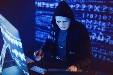 Hacker karanlık odada bilgisayar kullanıyor.