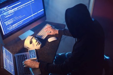 Hacker karanlık odada bilgisayar kullanıyor.