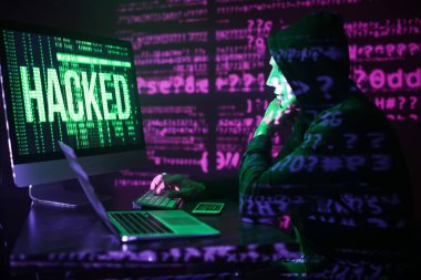 Hacker karanlık odada bilgisayar kullanıyor.