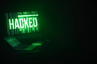 Bilgisayarlı ve cep telefonlu bilgisayar, karanlık odadaki hackerların iş yerinde.