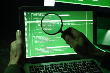 Bilgisayar kullanan büyüteçli bir hacker