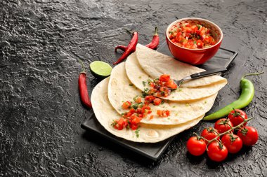 Koyu arkaplanda tortilla ile bir kase lezzetli salsa sosu.