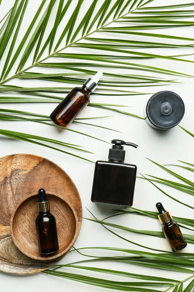 Hafif arkaplanda farklı kozmetik ürünler ve palmiye yaprakları