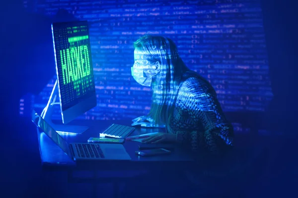 暗室でハッキングされたコンピュータの近くに座っている女性 — ストック写真