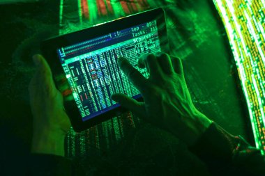 Koyu arkaplanda tablet bilgisayarı olan hacker elleri