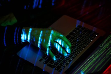 Hacker karanlık odada bilgisayar kullanıyor.