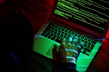 Hacker karanlık odada bilgisayar kullanıyor.