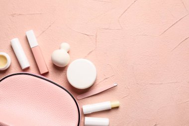 Renk arkaplanında makyaj malzemesi olan çanta