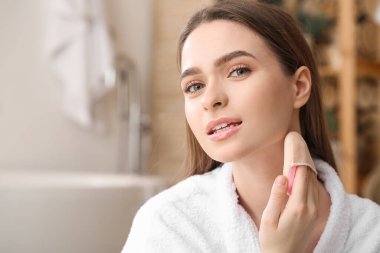 Güzel genç bir kadın banyoya makyaj yapıyor.