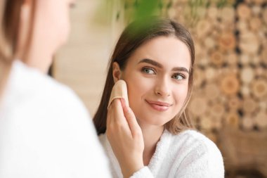 Güzel genç bir kadın banyoya makyaj yapıyor.