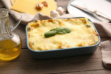 Lezzetli yeşil lazanya ve ahşap arka planda malzemelerle pişirme yemeği.