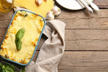 Ahşap arka planda lezzetli yeşil lazanyalı fırın yemeği.