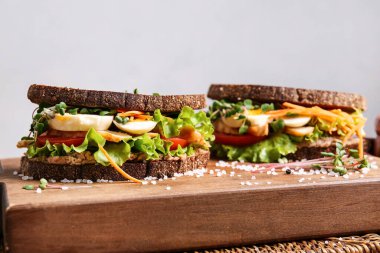 Hafif arka planda lezzetli sandviçleri olan tahta, yakın plan.