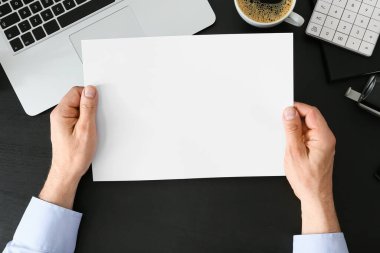 Karanlık arka planda boş kağıt tutan adam, yakın plan.