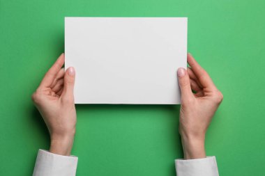 Renk arkaplanı üzerine boş kağıt tutan kadın, yakın plan