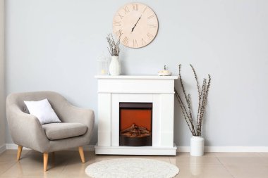 Odanın içinde söğüt dalları olan modern şömine ve vazolar.