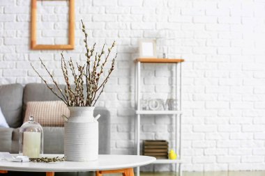 Oturma odasının içinde söğüt dalları olan bir vazo.