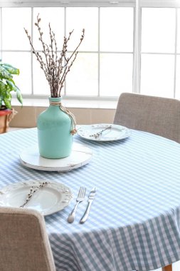 Yemek odasındaki masada söğüt dalları olan vazo.