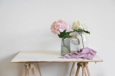 Işık duvarının yanındaki masada ortanca çiçekli vazo.