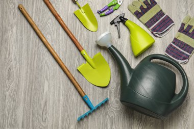 Gri ahşap arka planda sulama kutusu ve bahçe aletleri