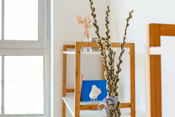 Vase with willow branches in interior of room