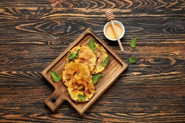 Izgara ananas dilimleri ve ahşap arka planda bal olan tahta.