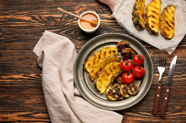 Izgara ananas dilimleri ve ahşap arka planda sebzeli tabak.