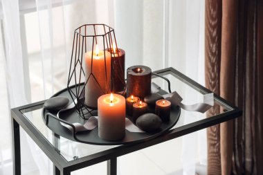 Pencerenin yanındaki masada yanan mumlar ve spa taşları