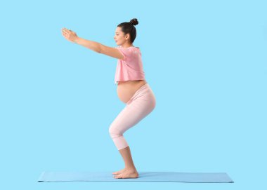 Genç hamile kadın arka planda yoga yapıyor.
