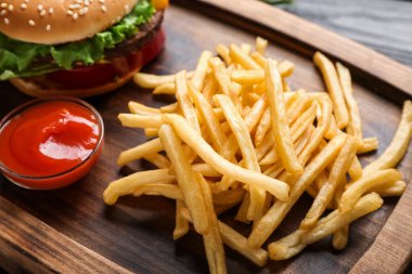 Lezzetli patates kızartması, domates sosu ve ahşap tahtada hamburger.