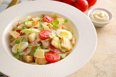 Renkli arka planda Sezar salatası ve sos tabağı, yakın plan.