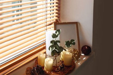 Pencerenin kenarına ağaç dalları ve çerçeve ile mum yakmak