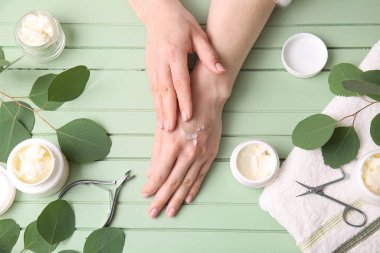 Renkli ahşap arka planda ellerine Shea yağı süren kadın.