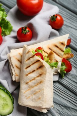 Renkli ahşap arka planda lezzetli donör kebap ve sebzeler, yakın plan.