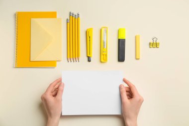 Renk arkaplanı üzerinde boş kağıt ve kırtasiye malzemesi olan kadın elleri