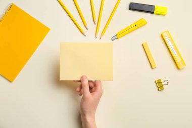 Renk arkaplanı üzerinde boş kağıt ve kırtasiye malzemesi olan kadın eli