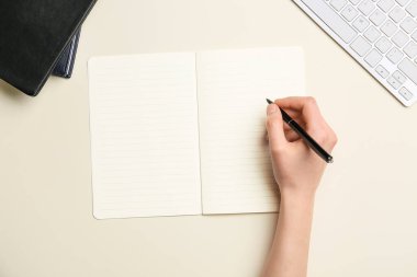 Renk arkaplanı üzerinde boş defter, klavye ve kalem bulunan kadın el