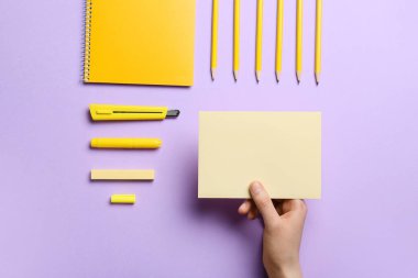 Renk arkaplanı üzerinde boş kağıt ve kırtasiye malzemesi olan kadın eli