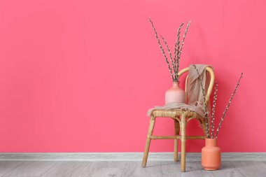 Renk duvarının yanındaki sandalyede söğüt dalları olan vazolar