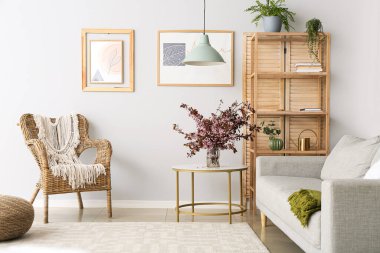 Oturma odasının içinde vazo ve çiçek açan dallar var.