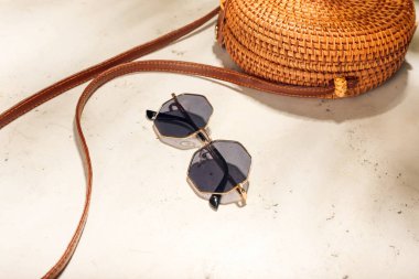 Işık arkaplanındaki güneş gözlüğü ve çanta şık