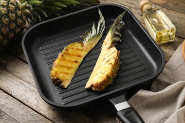 Ahşap arka planda ızgara ananas dilimleri ile kızartma tavası.