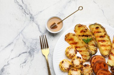 Izgara ananas dilimleri ve hafif arka planda sebzeli tabak.