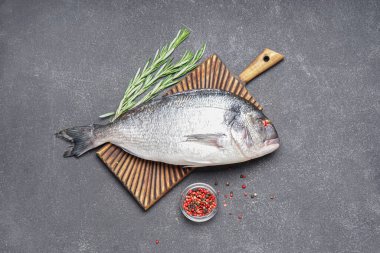 Koyu arkaplanda çiğ dorado balığı olan tahta