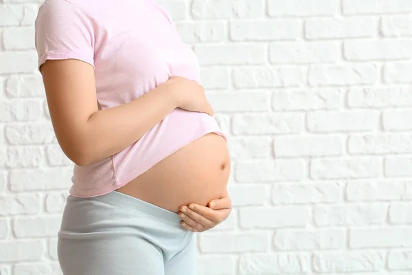 若いです妊娠中の女性オンレンガ背景 — ストック写真