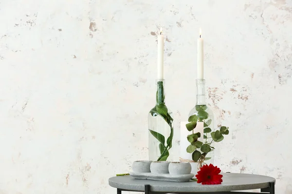靠近轻墙的桌上有花卉和植物枝条的蜡烛 — 图库照片