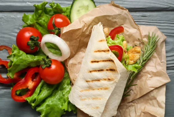 Tasty doner kebab with vegetables on color wooden background, closeup