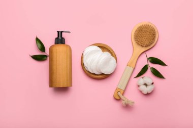 Renkli arka planda pamuk pedleri, fırçası ve bir şişe kozmetik ürünü olan tutucu