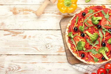 Hafif ahşap arka planda lezzetli vejetaryen pizzalı bir pano.